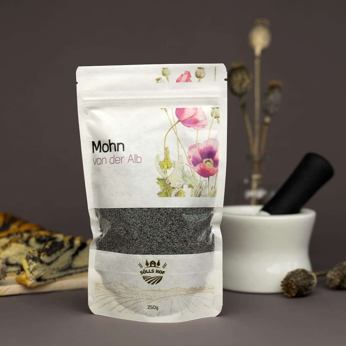 Mohnsamen stehen in Verpackung vor einem Mohnzopf.